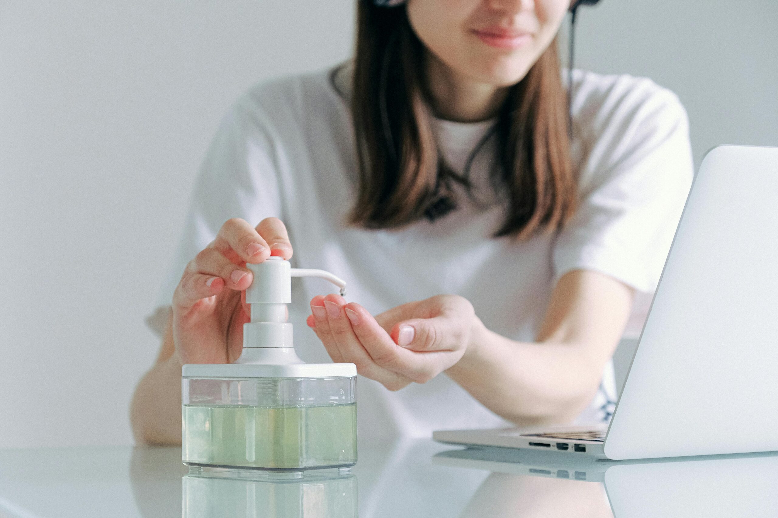 Woman applying hand sanitizer while working from home, embodying hygiene and safety.